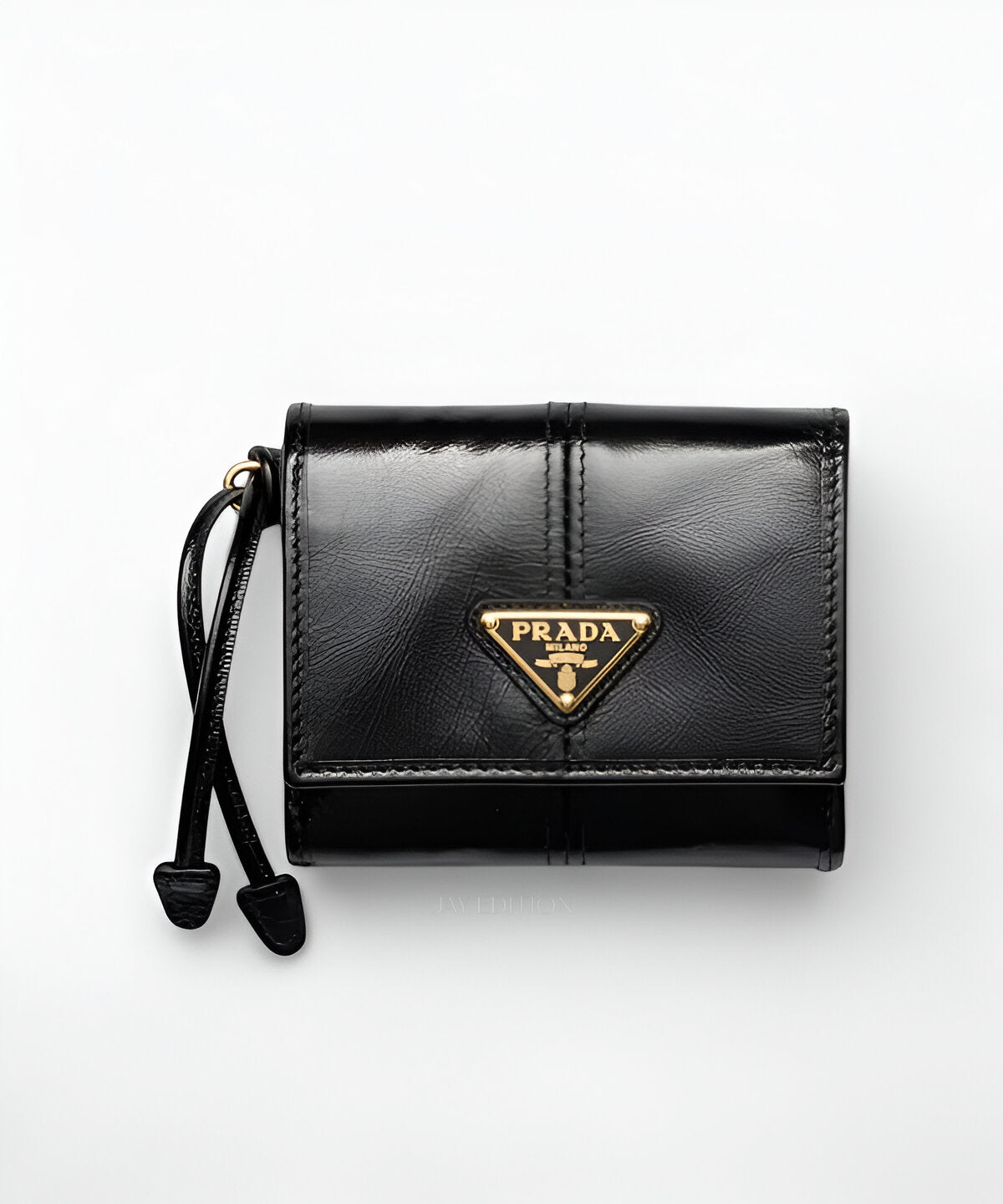 프라다 스몰 소프트 럭스 지갑, 부드러운 소프트 럭스 가죽으로 제작된 컴팩트한 플랩형 지갑으로, 프론트에 프라다 메탈 로고가 정교하게 장식되어 있으며, 내부에는 카드 슬롯, 지폐 수납 공간, 버튼 여밈의 동전 포켓이 포함된 우아하고 실용적인 디자인